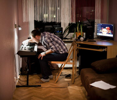 Lukasz Gibski, of Stereo disco polo band at his flat playing his keyboard. Disco polo is a type of dance music which originated in rural areas of Poland. Though considered tacky by many people, it is...