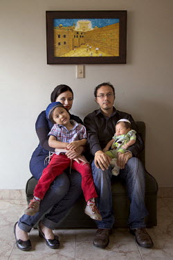 Ezra Rodriguez with his wife, Yehudit Zapata, with their two sons, four year old Yoetzel and Aharon, three months. recites prayers in a synagogue. They belong to a community, one of many worldwide, of...