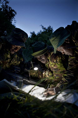Rangers on the Lewa Wildlife conservancy on a night patrol check a grid reference with a torch. They are looking out for poachers who usually strike at night time. The Lewa Wildlife Conservancy, a non...