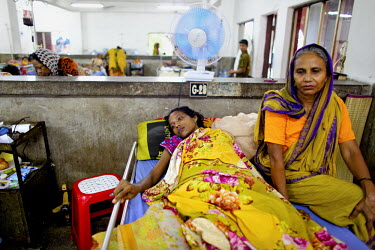 One of the survivors of the collapsed Rana Plaza complex rests in her bed in the Pongu Hospital in Dhaka with a relative sitting by her side. Both of her legs were injured in the accident and it is do...