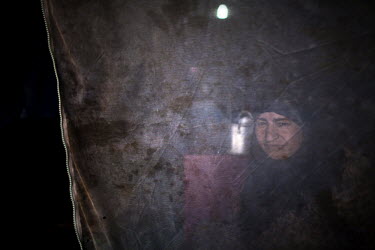A woman seen through a curtain in her tent. Domiz Refugee Camp run by UNHCR was established by local authorities in April 2012 to host the Syrian Kurds. The camp located 20 kms southeast of Dohuk city...