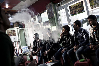 Young men smoke shisha at a traditional cafe.