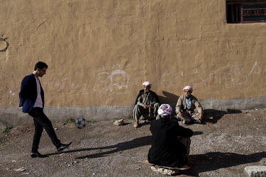 A young man kicks a football as elderly Yazidi men sit on the ground. The Yazidi are a Kurdish ethno religious group. They adhere to a branch of Yazdanism that blends elements of Mithraism, pre-Islami...