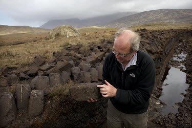 A man points out the structures on a block of peat turf, cut from a bog between Letterfrack and Leenane.