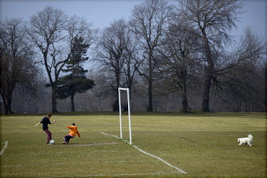 Two brothers, with their pet dog closeby, play football in Moor Park, Preston, Lancashire.