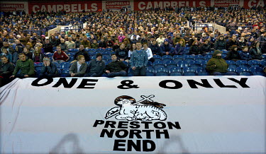 Fans sitting behind a huge flag featuring the Preston North End football club crest and the slogan 'One and Only' at the Deepdale Stadium, Lancashire. The football club was founded in 1863 and they pl...