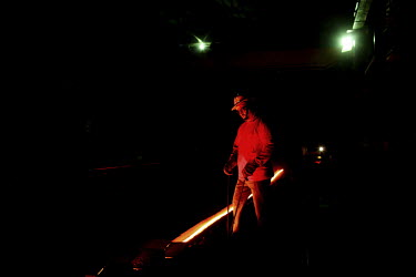 A workers glows with the light from a furnace making new metal rods at a steel recycling and re-rolling factory in Dhaka.