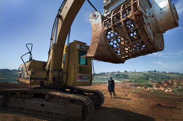 A deminer, working for Mines Action Group's (MAG) Battle Area Clearance (BAC) team 3, looks at their specially adapted amoured digger. Its rotary screening bucket scoops up soil suspected to contain m...
