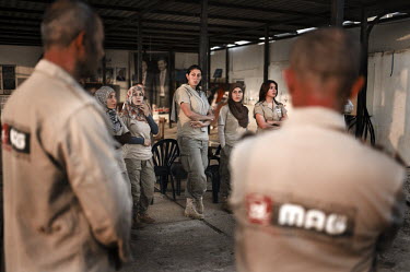 Women deminers from the Mines Action Group's (MAG) Battle Area Clearance (BAC) team 3 listen to the morning briefing prior to starting the day's work.