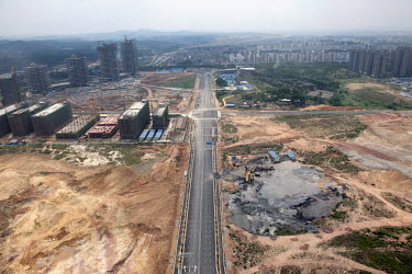 An area of land cleared for building is bisected by a six-lane highway.