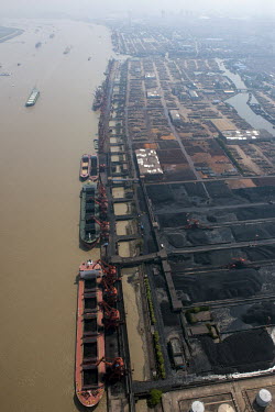 Coal barges are  loaded by cranes from storage depots alongside the Yangtze River.