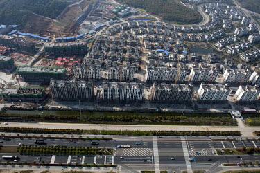 A six-lane highway passes a zone where highrise apartments and housing estates are being built.