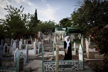 A woman stands next to a grave at a cemetery in Sulaymaniyah.