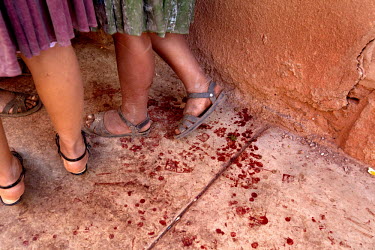 Women stand next to drops of human blood on a pavement in Macha during the <i>tinku</i> festival.   The people of Macha and surrounding communities carry on the pre-Columbian tradition of ritual fight...
