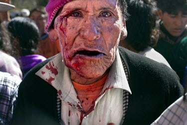 Blood streams from the face of an elderly fighter participating in the ritual fighting in the plaza of Macha.   The people of Macha and surrounding communities carry on the pre-Columbian tradition of...