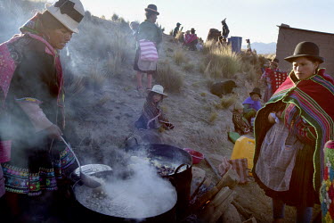Women cook while men dance in a hillside community near Macha during the <i>tinku</i> festival.   The people of Macha and surrounding communities carry on the pre-Columbian tradition of ritual fightin...