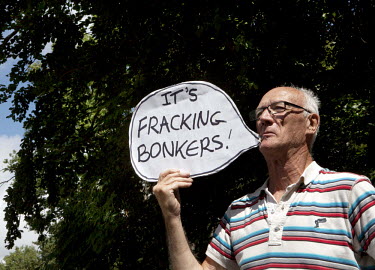 A man protesting, in the West Sussex village of Balcombe, against oil exploration and hydraulic fracturing (fracking) holds a handmade 'speech bubble' sign with a pun that reads: 'It's fracking bonker...