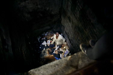 A homeless person stands among a pile of rubbish.