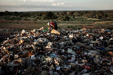 A woman picks through a rubbish dump in a search for recyclable items.