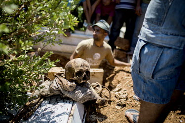 A human skull and bones sit on the side of a grave in Bab al-Tabbaneh during the funeral of 16 year old who was killed in a car bomb attack on the Taqwa Mosque on 23 August 2013.