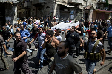 Men, some armed with automatic weapons, accompany the body of a 16 year old through the streets of Bab al-Tabbaneh during the funeral procession. The victim died when a car bomb was detonated outside...
