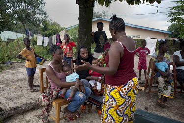 Traditional Birthing Attendant Mabinty M. Kamara (maroon top) talks with H4+ benificary Baratu Lee (in black) and other women in Makeni, Bombali District. The H4+ (made up of UNAIDS, UNFPA, UNICEF, UN...