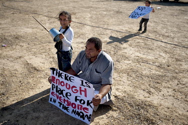 A man and his children bang tins and hold placards during a protest against the 'Prawer Plan', near the unrecognised Bedouin village of El-Arakib. The Prawer Commission, chaired by Ehud Prawer, Benjam...