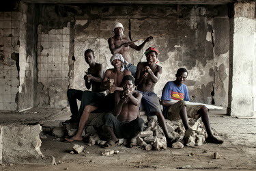 A group of former child soldiers in the gutted remains of the Euro Bank building. Pictured: Stevein Lews, 28, (top of group wearing white bandana, also known as 'Chucky'), Amos Harris, 27, (far left,...