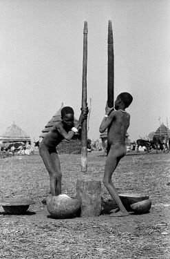 Nuer girls pounding maize in a cattle camp on the banks of the Baro River. They rub ash on their skin as protection against biting flies. The Nuer are traditionally cattle breeders and migrate, betwee...
