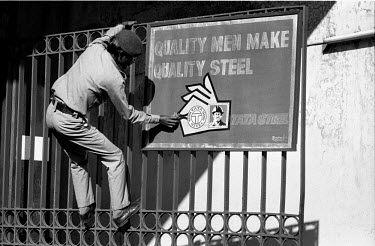 A security guard cleans a sign at the entrance to the Tata Steel iron ore mine.