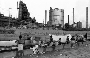 At the Jamshedpur Tata Steel plant women, from one of the region's many indigenous tribal peoples (Adivasi), take advantage of heated waste water to wash clothes and sheets.