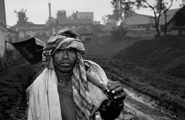 A labourer with a shovel over his shoulder at Tata Steel's Jamadhoba coal mine