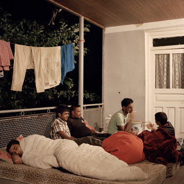 Punjabi farm workers employed by Indian farmer and landowner Ranjod Kamboj, sleep and talk on the porch of the house they share in the village of Kurtlari. The men live near land where they harvest cr...
