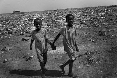 Two boys walk hand-in-hand across a rubbish strewn field in the 'Washington D.C.' IDP camp outside Garowe, a town in the self-declared autonomous state of Puntland. The IDP camp on the other side of t...