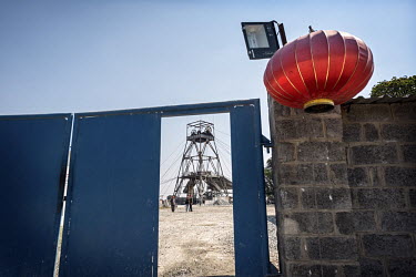 A Chinese lattern hangs from a wall at the Chinese-owned NFCA (Non-Ferrous Company Africa) headquarters at the Chambishi copper mine. A newly built mine shaft winding tower is in the background. The N...