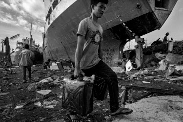 A man carries water canisters past one of a number of ships that have been washed up by the storm surge in Tacloban City. Typhoon Haiyan, or Typhoon Yolanda as it is known in the Philippines, was the...