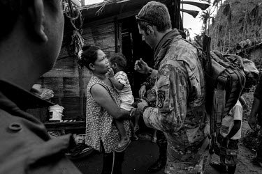 Sergeant Mascia, a medic from the US Green Berets, checks a sick child and discusses his condition with his mother. The child was later evacuated by helicopter to a hospital. Typhoon Haiyan, or Typhoo...