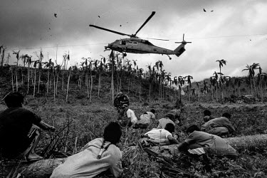 People take cover as a US helicopter full of relief supplies lands in Mahagnau village, Leyte. Many remote villages had to wait for a number of days to receive relief goods. Typhoon Haiyan, or Typhoon...
