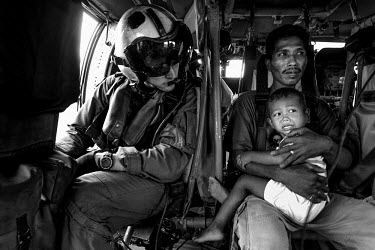 Sergeant Mascia, a medic from the US Green Berets, sits next to a sick child and its father as they are airlifted to a nearby hospital. Typhoon Haiyan, or Typhoon Yolanda as it is known in the Philipp...