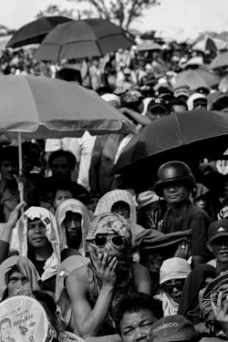 People watch a fight between Philippine boxers Pacquiao and Rios on a screen erected in the centre of Tacloban. Some are shielding from the sun under umbrellas. Typhoon Haiyan, or Typhoon Yolanda as i...