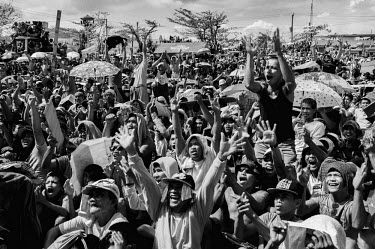 People cheer while watching a fight between Philippine boxers Pacquiao and Rios on a screen erected in the centre of Tacloban. Some are shielding from the sun under umbrellas. Typhoon Haiyan, or Typho...