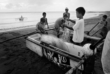 Children check nets next to a boat made out of an old refrigirator. Francis Kyle, a fisherman in Tanauan, noticed a floating fridge. He found a couple amongst the debris in the town and fasioned a sma...