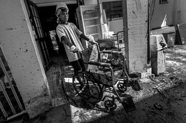 A worker at Tacloban Hospital wheels a damaged wheelchair around the grounds of the hospital. Much of the hospital was submerged in the storm surge. Typhoon Haiyan, or Typhoon Yolanda as it is known i...