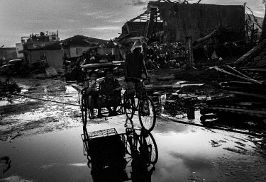 Two women sit in the back of a bicycle rickshaw riding through the destroyed streets of Tacloban. Typhoon Haiyan, or Typhoon Yolanda as it is known in the Philippines, was the deadliest typhoon to hit...