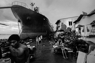 People sit around next to destroyed buildings and a beached ship which was washed ashore by the sturm surge. Typhoon Haiyan, or Typhoon Yolanda as it is known in the Philippines, was the deadliest typ...