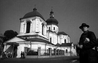 A man stands next to St Mikolai, an Orthodox Church in Kiev, while other worshippers file in. The church was used as a storage facility during Soviet times since religion was officially banned. The ch...