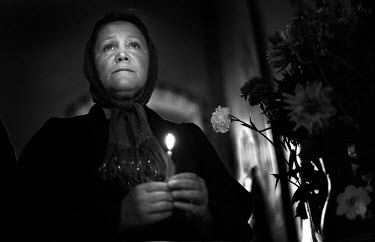 A woman holds a candle while praying during a church service in St Mikolai, a large Orthodox church in Kiev. The church was used as a storage facility during Soviet times since religion was officially...