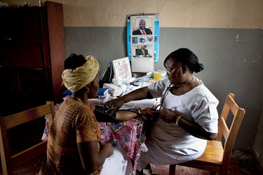 Midwife Zainab Manserray takes the blood pressure of a pregnant patient. Manserray is in charge of the Masougbo Chiefdom Primary Health Unit in Bombali District, and is currently training a male midwi...