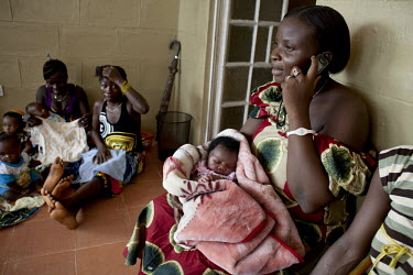 A woman uses a mobile phone while pregnant women and new mothers wait to be seen at San Malen Primary Health Unit in Pujehun. The unit is supported by H4+ (made up of UNAIDS, UNFPA, UNICEF, UN Women,...