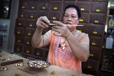 A woman measures out ingredients used in Chinese traditional medicine.
